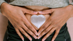 Image of person's hands in a heart shape over their belly